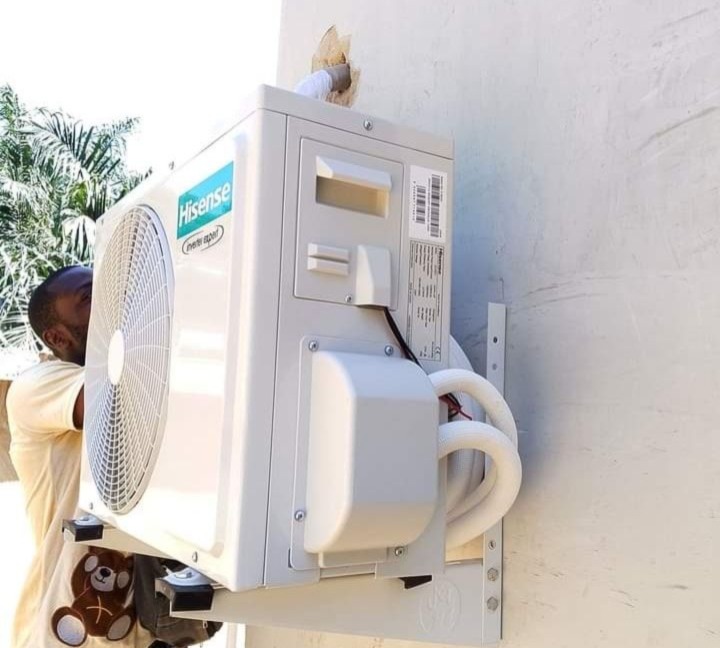 Technician mounting a Hisense outdoor AC unit on a wall bracket